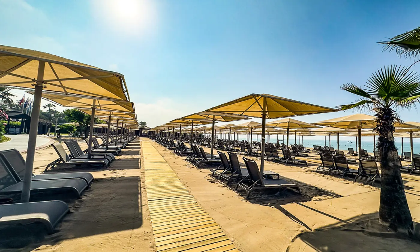 Sunbeds and umbrellas on the private beach at Gloria Verde Resort